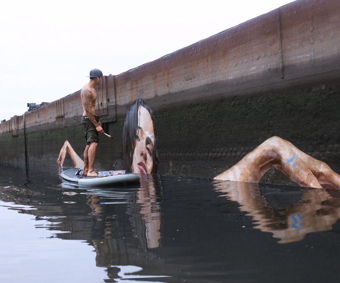 Este artista pinta asombrosos murales a nivel del mar sobre una tabla de surf 